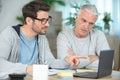 smiling father and son with laptop while sitting at desk