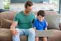 Smiling father and son sitting on sofa using laptop in living room Royalty Free Stock Photo
