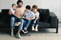 smiling father and sons reading book together