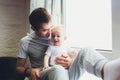 Smiling Father Standing By Window With Baby Son At Home. Royalty Free Stock Photo