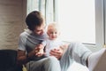 Smiling Father Standing By Window With Baby Son At Home. Royalty Free Stock Photo