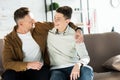 Smiling father and teen son hugging on sofa at home and looking Royalty Free Stock Photo