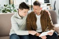 Smiling father and teen son looking at tablet