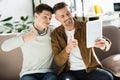 Smiling father and teen son looking at tablet and showing thumbs up Royalty Free Stock Photo