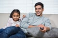 Smiling father watching tv with daughter on the sofa