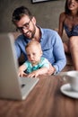 Smiling father working with computer while looking after his baby son.. Royalty Free Stock Photo