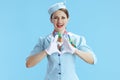 smiling female air hostess on blue showing heart hands Royalty Free Stock Photo