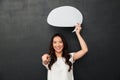 Smiling female asian holding blank speech bubble above her head