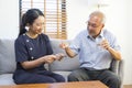 Female asian nurse takes care of sick senior man, help to remind to take a pill. Royalty Free Stock Photo