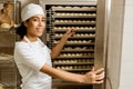smiling female baker pointing at dough inside of industrial oven Royalty Free Stock Photo