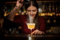 Smiling female bartender pouring a spice to the delicious cocktail Royalty Free Stock Photo