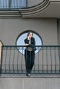 Smiling female boss in black pantsuit on the balcony. Middle-aged woman in formal business clothing