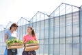 Smiling female botanists carrying plants in wooden crates against greenhouse