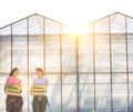 Smiling female botanists carrying plants in wooden crates against greenhouse