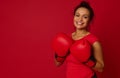 Smiling female boxer, pretty woman wearing red boxing gloves smiles toothy smile looking at camera,  over colored Royalty Free Stock Photo