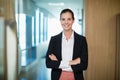 Smiling female business executive standing with arms crossed in corridor Royalty Free Stock Photo