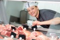 smiling female butcher labelling joints meat in counter