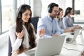 Smiling female call center operator in headphones with microphone consulting client on phone in customer support service while Royalty Free Stock Photo
