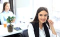 Smiling female call centre operator doing her job with a headset while looking at camera. Royalty Free Stock Photo