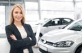 Smiling female car dealer posing in front of new automobiles Royalty Free Stock Photo