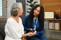 Smiling female caregiver checking blood glucose levels of senior diabetic woman during a home visit. Diabetes and health Royalty Free Stock Photo