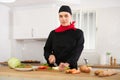 Smiling female chef in black uniform preparing vegetable salad in private kitchen Royalty Free Stock Photo