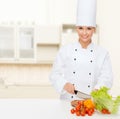 Smiling female chef chopping vegetables