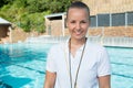 Smiling female coach standing near poolside