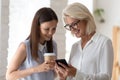 Smiling female colleagues browse smartphone at office coffee break Royalty Free Stock Photo