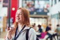 Smiling Female College Student Talking Into Mobile Phone In Busy Communal Campus Building Royalty Free Stock Photo