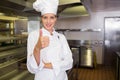 Smiling female cook gesturing thumbs up in kitchen Royalty Free Stock Photo