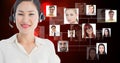 Smiling female customer care representative wearing microphone against flying business portraits Royalty Free Stock Photo