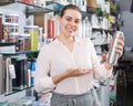 Smiling female customer choosing ware for wine bottle