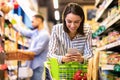 Young lady with mobile phone shopping at super market Royalty Free Stock Photo