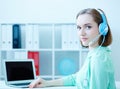 Smiling female customer support phone operator sitting at office workplace half turn looking in camera portrait. Royalty Free Stock Photo