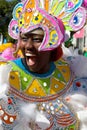 Smiling female dancer dressed in huge pink headdress, dances in Junkanoo