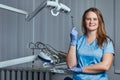 Smiling female dentist holding dental mirror while standing in her dentist office. Royalty Free Stock Photo