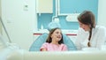 Smiling female dentist talking with lovely little girl