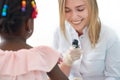 Smiling female doctor checking skin of little afro girl.