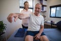 Smiling female doctor examining shoulder of senior male patient Royalty Free Stock Photo