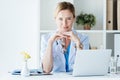 smiling female doctor in eyeglasses looking at camera at table with laptop Royalty Free Stock Photo