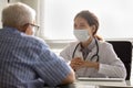 Smiling doctor in facemask consult senior male patient Royalty Free Stock Photo