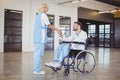 Smiling female doctor handshaking with doctor sitting on wheelchair Royalty Free Stock Photo