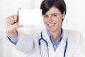 Smiling female doctor holding a business card or white pill box Royalty Free Stock Photo