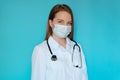 Smiling female doctor in lab coat with arms crossed against blue background