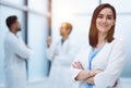 Smiling female doctor in lab coat with arms crossed against Royalty Free Stock Photo