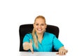 Smiling female doctor or nurse sitting behind the desk with hand redy to handshake Royalty Free Stock Photo