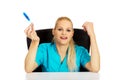 Smiling female doctor or nurse sitting behind the desk and holding thermometer Royalty Free Stock Photo