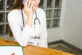 Smiling Female Doctor Relaxing at her Office While Calling to Someone Using a Mobile Phone close-up. Royalty Free Stock Photo