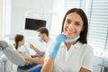 Smiling female doctor showing looking at the camera while her collegue working with girl in dental chair on the background Royalty Free Stock Photo
